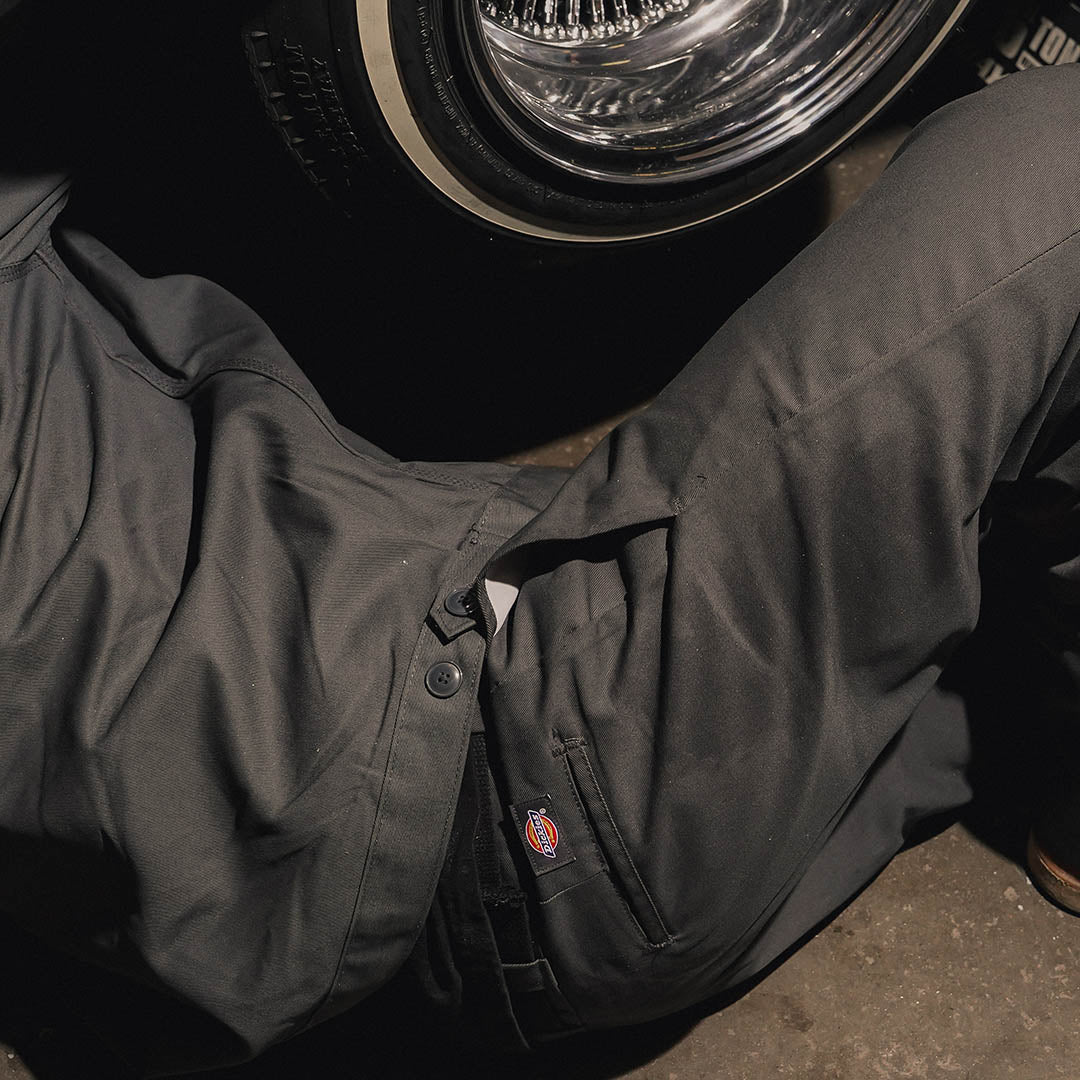 Dark workwear beside a classic wheel